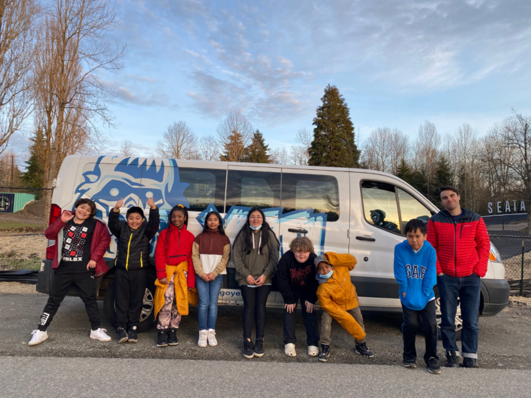 Group of students standing and smiling in front of a Y.E.T.I. van